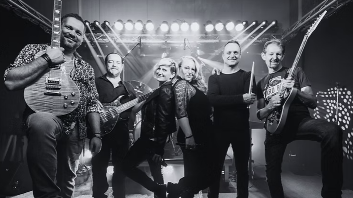 Eine Band posiert in einem Studio mit Gitarren. Im Hintergrund sind Lichter zu sehen, die eine lebendige Atmosphäre schaffen. | © Tourismus Oststeiermark