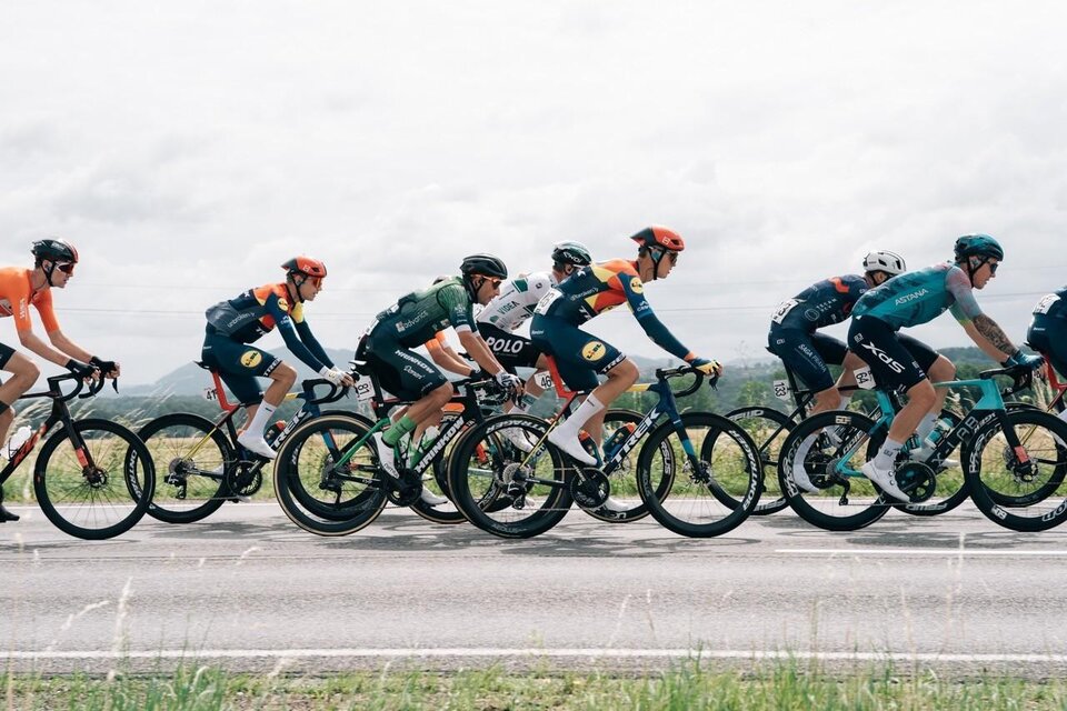 Eine Gruppe von Radfahrern fährt in einem Wettkampf auf einer Straße. Der Himmel ist bewölkt und die Landschaft im Hintergrund ist grün. | © EXPA