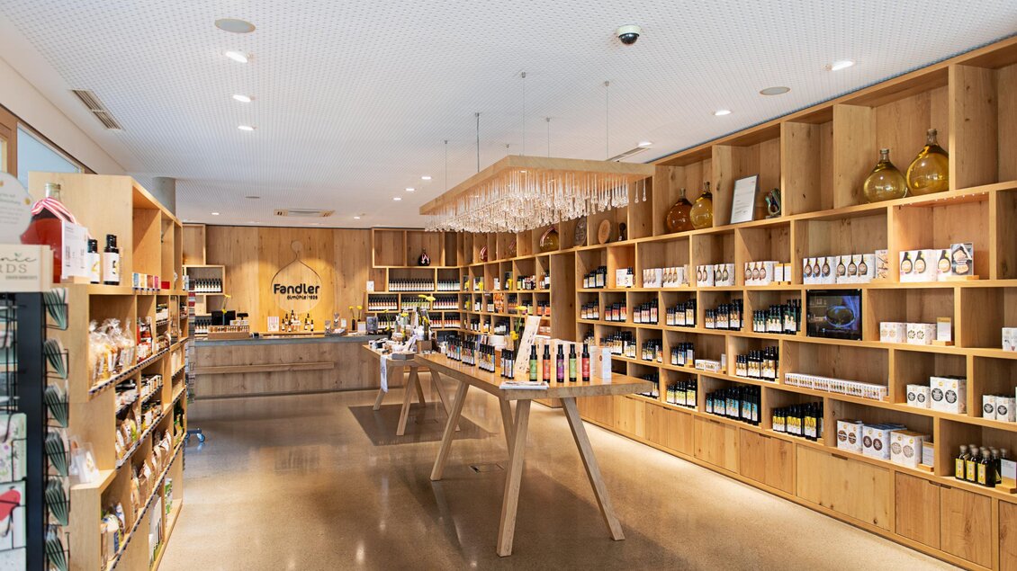 Ein moderner Laden mit Holzregalen, die verschiedene Produkte präsentieren. Die Beleuchtung ist hell und freundlich, mit einem einladenden Ambiente. | © Öhlmühle Fandler