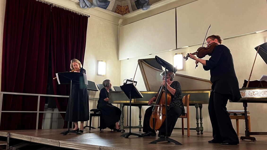 Ein Ensemble spielt auf einer Bühne in einem historischen Raum mit beeindruckenden Wandmalereien. Die Musizierenden bestehen aus einer Flötistin, einem Geiger, einem Cellisten und weiteren Instrumentalisten. | © Tage der Alten Musik