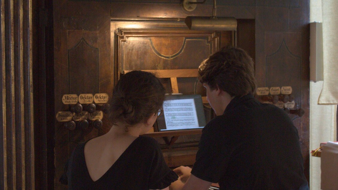Zwei Personen sitzen vor einer Orgel und betrachten einen Bildschirm. Die Atmosphäre ist entspannt und kreativ. | © Tage der alten Musik