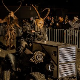 Eine kreative Parade mit Menschen in Kostümen und Masken, die auf einem Traktor fahren. Im Hintergrund sind viele Zuschauer zu sehen. | © Tv Murau