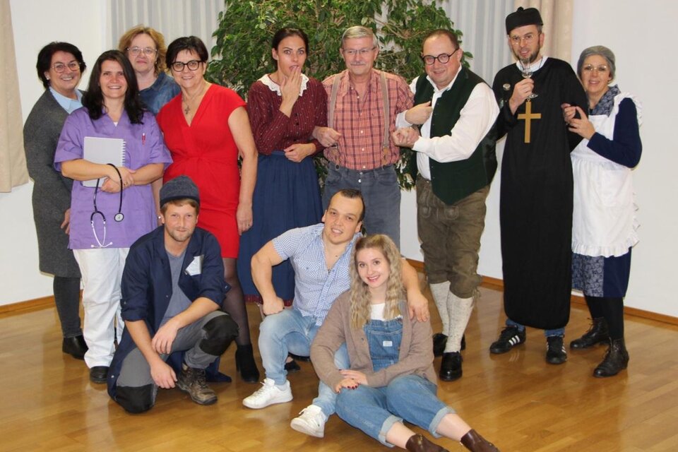 Eine Gruppe von zwölf Personen steht zusammen in einem Raum. Einige von ihnen tragen verschiedene Kostüme, darunter medizinische und historische Kleidung. | © Theaterverein "Wir theatern wieder"