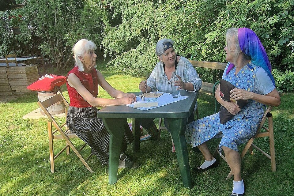 Drei Frauen sitzen entspannt im Garten an einem Tisch. Sie scheinen ein Spiel oder eine Aktivität zu genießen. | © TRUNK-Elfi Greiner