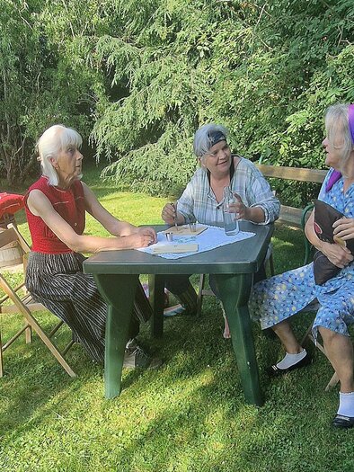 Drei Frauen sitzen entspannt im Garten an einem Tisch. Sie scheinen ein Spiel oder eine Aktivität zu genießen. | © TRUNK-Elfi Greiner