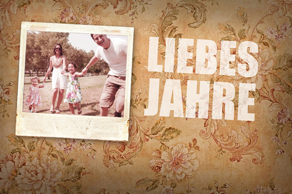 Eine Familie hält Händchen und lächelt fröhlich im Freien. Im Hintergrund ist eine blühende Landschaft zu sehen. | © a.gon Theater