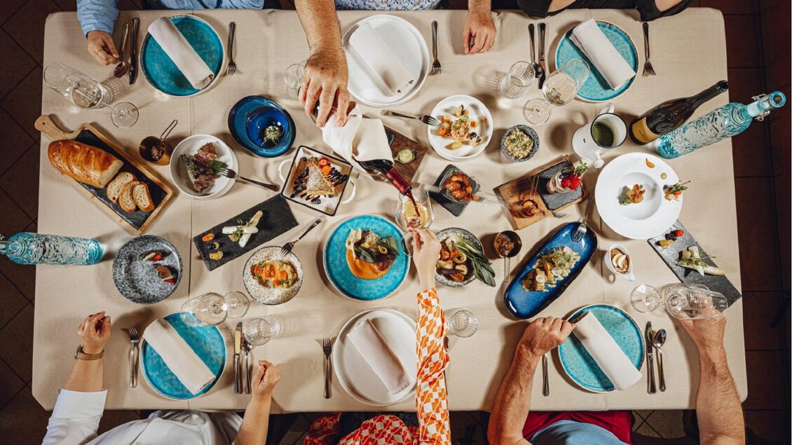 Ein gedeckter Tisch mit verschiedenen Gerichten und Getränken. Menschen sitzen zusammen und genießen eine gemeinsame Mahlzeit. | © Tischlein deck dich_Oststeiermark