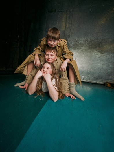 Three children are playfully posing on the floor. They are wearing simple clothing and have cheerful facial expressions. | © -marko-mestrovic.