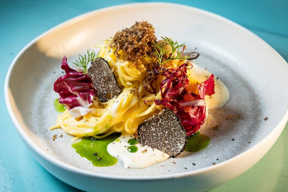 Ein eleganter Teller mit Pasta, garniert mit Radicchio, Kräutern und schwarzem Trüffel. Die Anrichtung ist ansprechend und farbenfroh, mit einer cremigen Sauce. | © Graz Tourismus - Werner Krug