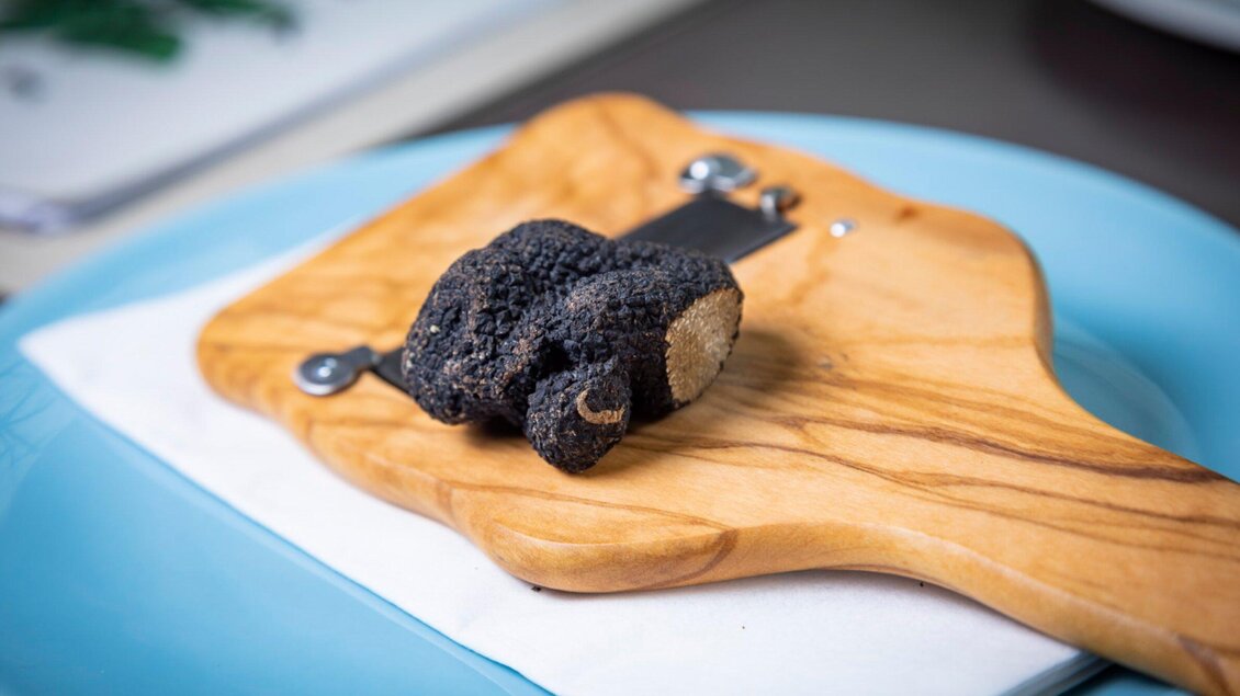 Eine frische schwarze Trüffel liegt auf einem Holzbrett. Der Hintergrund ist unscharf und vermittelt eine elegante Atmosphäre. | © Graz Tourismus_Werner Krug