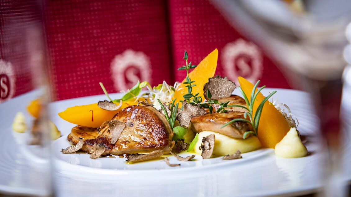 Ein elegantes Gericht mit zartem Fleisch, serviert mit Kürbis und frischen Kräutern. Die Anrichtung ist ansprechend und stilvoll. | © Graz Tourismus - Werner Krug