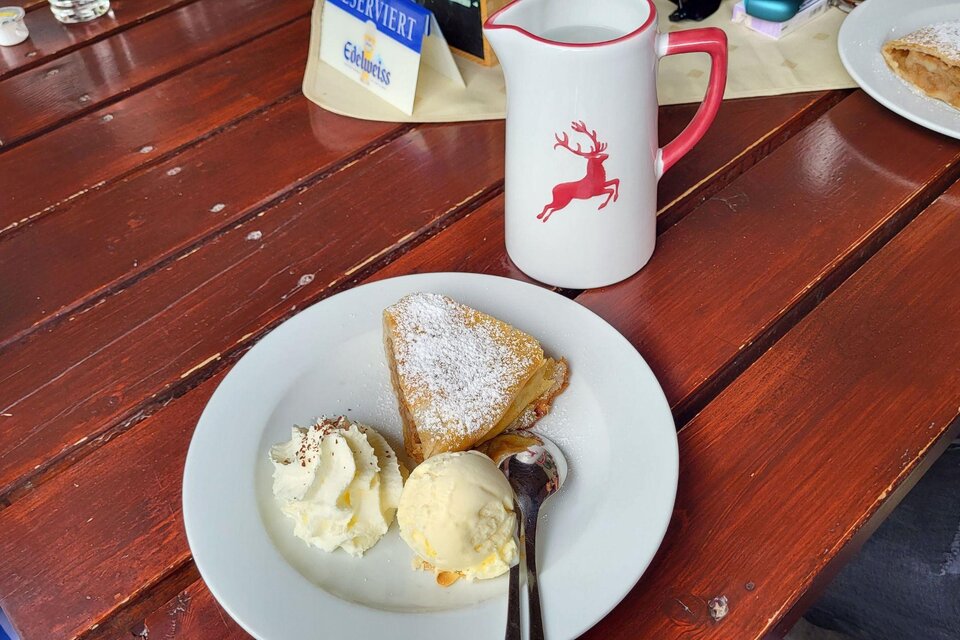 Ein Teller mit einem Stück Kuchen, Sahne und einer Kugel Eis. Dazu steht eine Kanne mit einem Rentier-Motiv. | © Petra Kirchschlager