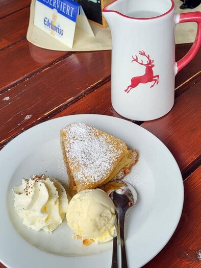 Ein Teller mit einem Stück Kuchen, Sahne und einer Kugel Eis. Dazu steht eine Kanne mit einem Rentier-Motiv. | © Petra Kirchschlager
