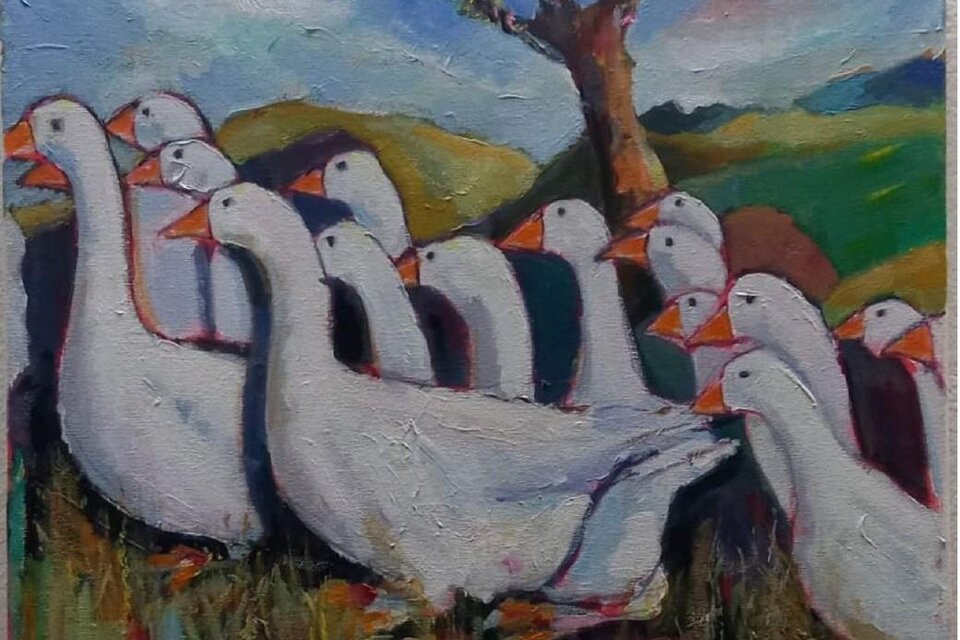 Eine Gruppe von weißen Gänsen steht auf einer Wiese. Im Hintergrund sind sanfte Hügel und ein Baum zu sehen.