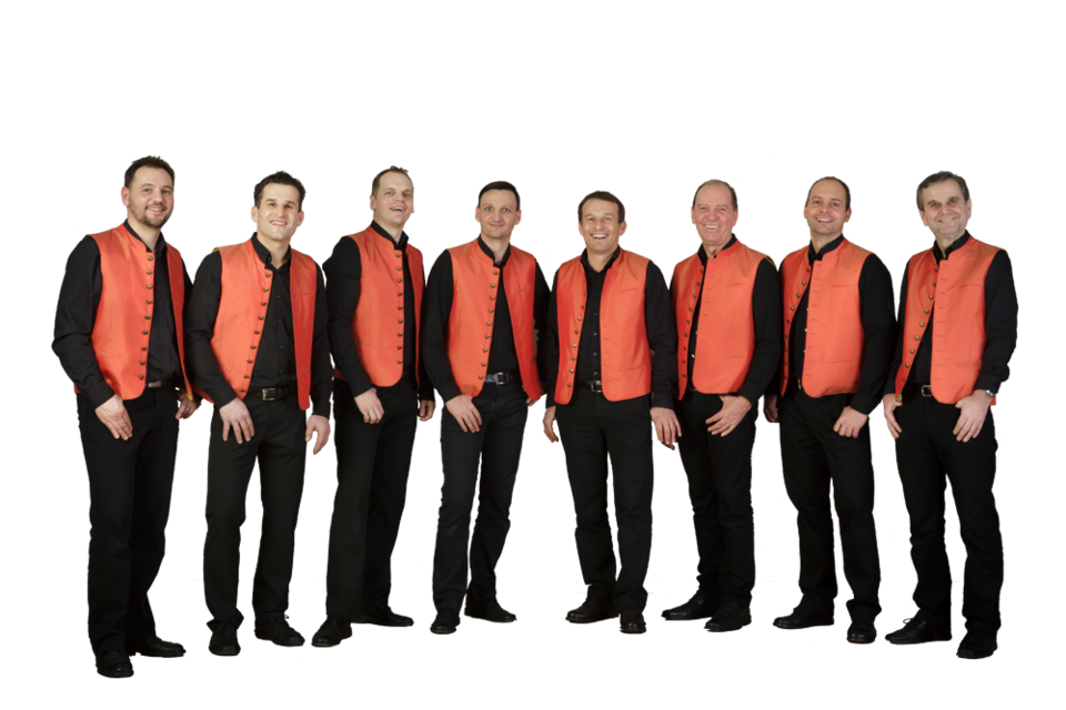 Eine Gruppe von acht Männern steht nebeneinander. Sie tragen schwarze Kleidung mit auffälligen orangefarbenen Westen.