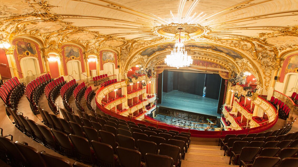 Ein prachtvolles Theater mit einem kunstvoll verzierten Innenraum. Die Reihen von roten Sitzplätzen sind um die Bühne angeordnet. | © Graz Tourismus - Harry Schiffer