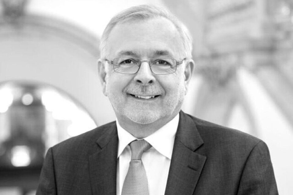 Ein lächelnder Mann in einem Anzug steht vor einem hellen Hintergrund. Sein Gesichtsausdruck wirkt freundlich und professionell. | © Harald Eisenberger