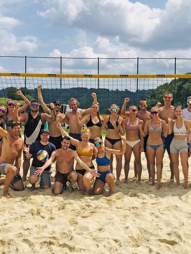 Gruppe junger Menschen jubelt auf einem Beachvolleyballplatz im Sand vor dem Netz – sommerliche Stimmung, Sport, Teamgeist und Freizeitspaß unter freiem Himmel in der Erlebnisregion Thermen- & Vulkanland. | © Christian Knittelfelder
