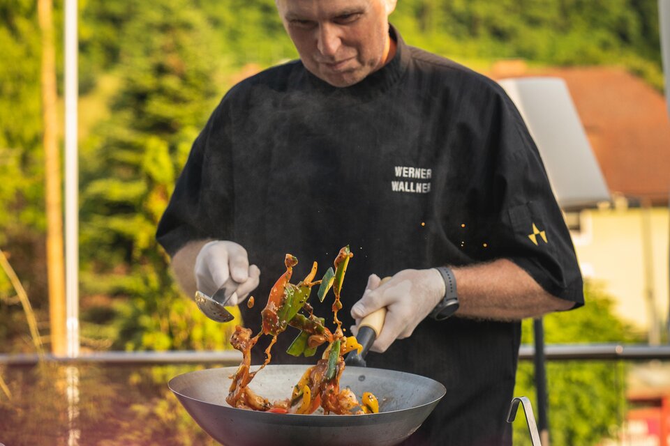 Ein Koch bereitet ein Gericht im Wok zu. Frisches Gemüse und Fleisch werden in der Pfanne geschwenkt. | © Vulkanlandhotel Legenstein