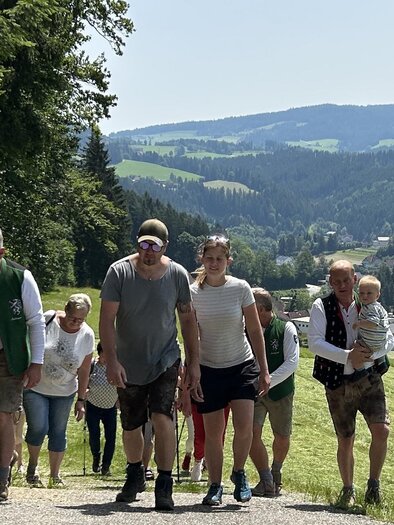 Eine Gruppe von Menschen wandert einen malerischen Weg entlang, umgeben von grünen Feldern und hügeliger Landschaft. Im Hintergrund ist eine kleine Stadt sichtbar. | © EDL-Event GmbH