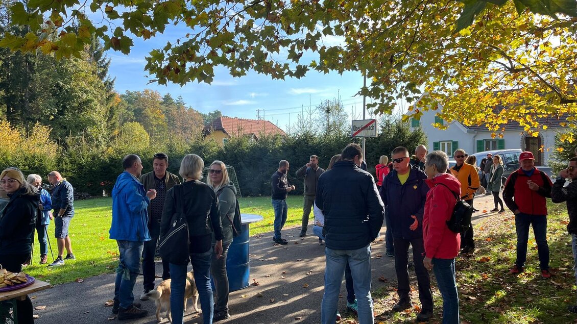 Eine Gruppe von Menschen steht im Freien unter einem Baum mit bunten Blätter. Es scheint einen geselligen Austausch zwischen den Teilnehmern zu geben. | © Mild