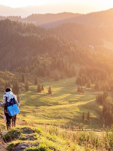 Zwei Wanderer gehen auf einem Pfad durch eine bergige Landschaft. Die Sonne scheint und sorgt für eine goldene Beleuchtung der Umgebung. | © pixabay.com