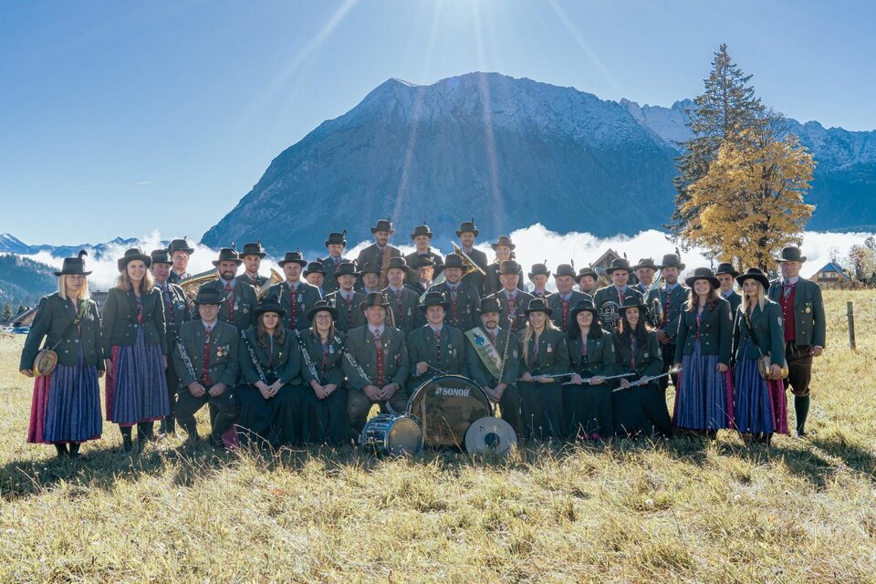 Eine Blaskapelle spielt auf einer Freiluftbühne. Die Musiker tragen traditionelle Kleidung in Rot und Schwarz. | © Trachtenkapelle Tauplitz