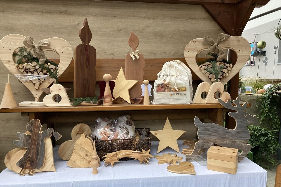 Weihnachtliches Kunsthandwerk aus Holz mit liebevoll gefertigten Engeln, Sternen, Herzen, Kerzen und Rentieren auf einem festlich dekorierten Adventstand. | © Samstagmarkt