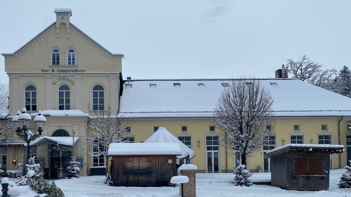 Das Kur-& Congresshaus Bad Aussee in einer winterlichen Landschaft. Im Vordergrund sind Hütten vom Weihnachtmarkt zu sehen. 
 | © TVB Ausseerland Salzkammergut  Beringer