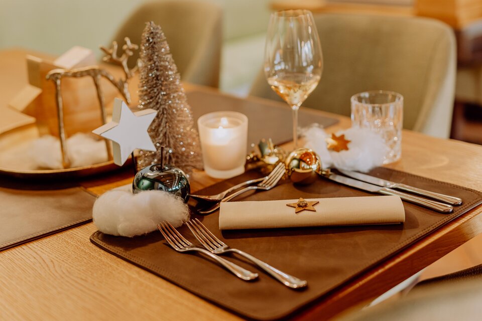 Ein festlich gedeckter Tisch mit Weihnachtsdeko, Gläsern und Besteck. Kleine Sterne und eine dekorative Tannenzweige verleihen der Atmosphäre einen besonderen Charme. | © Karin Bergmann