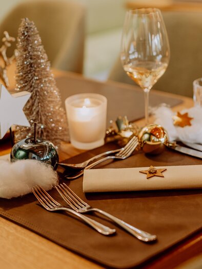 Ein festlich gedeckter Tisch mit Weihnachtsdeko, Gläsern und Besteck. Kleine Sterne und eine dekorative Tannenzweige verleihen der Atmosphäre einen besonderen Charme. | © Karin Bergmann