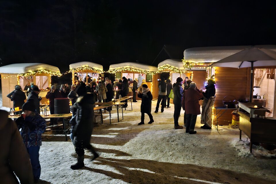 Ein festlich geschmückter Markt bei Nacht mit vielen Menschen, die sich unternehmen. Die Stände sind mit Lichtern beleuchtet und schaffen eine gemütliche Atmosphäre. | © Herbert Bieber