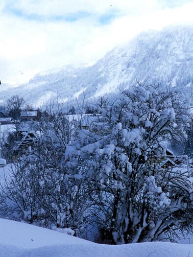 Eine verschneite Landschaft mit einem hohen Kirchturm. Im Hintergrund sind Berge und ein winterlicher Himmel zu sehen. | © TVB Ausseerland Salzkammergut_Pirker