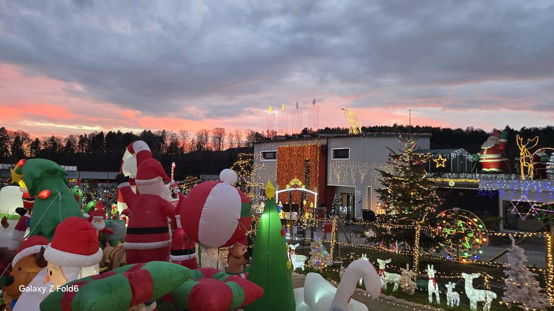 Eine festlich dekorierte Szene mit riesigen Weihnachtsfiguren und bunten Lichtern. Der Himmel färbt sich im Hintergrund in sanften Tönen während der Dämmerung. | © Wiesenhofer