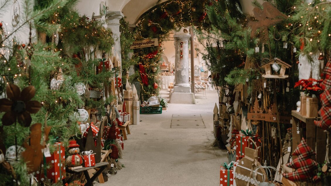 Weihnachtliches Kunsthandwerk im Schloss Burgau: Festlich geschmücktes Gewölbe mit Tannengrün, Lichterketten und liebevoll arrangierten Geschenk- und Dekorationsideen für die Adventzeit. | © Kunsthandwerk Schloss Burgau