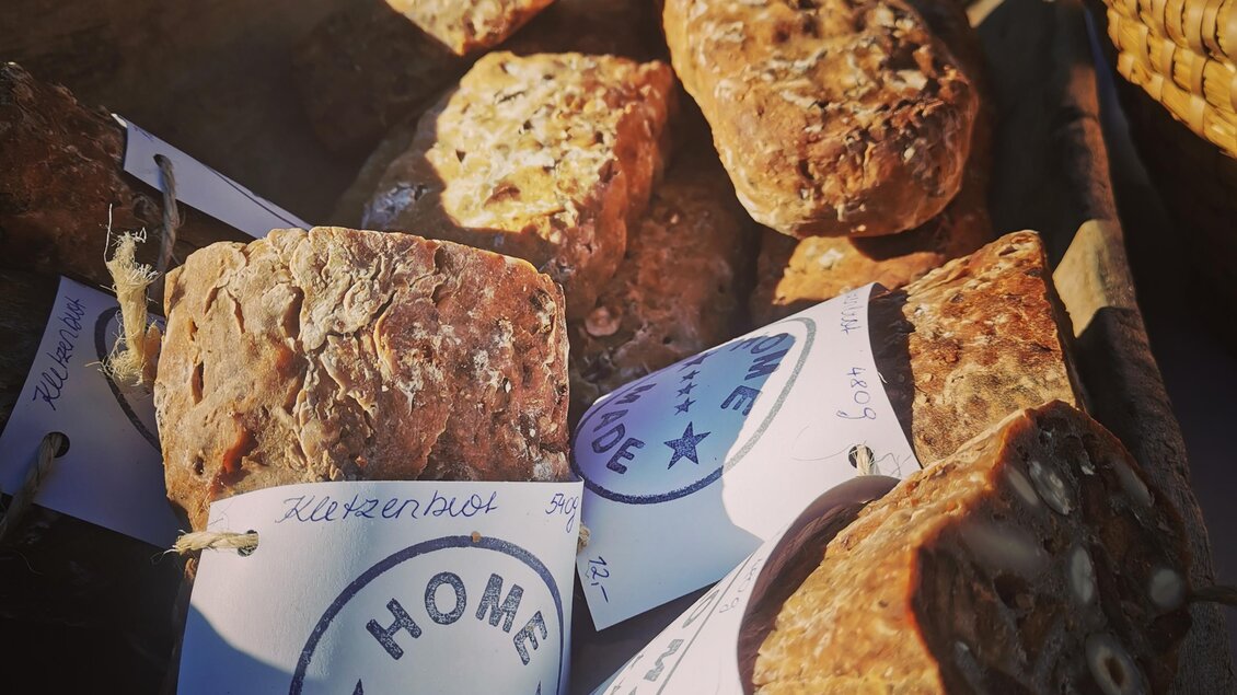 Eine rustikale Holzschale mit handgemachten Leckereien. Die Stücke sind beschriftet und mit Etiketten markiert. | © Tina Veit-Fuchs