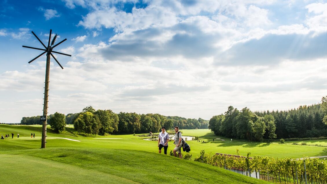 Eine weitläufige Golfanlage mit grünem Rasen und sanften Hügeln. Im Hintergrund sind zwei Golfer zu sehen, die den Platz genießen. | © Traminer Golf Klöch