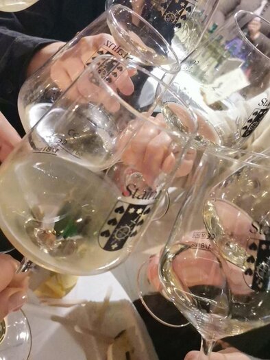 A group of people are raising glasses of champagne to toast. The glasses are labeled and there is a festive atmosphere. | © TV Südsteiermark - Irene Löschnig