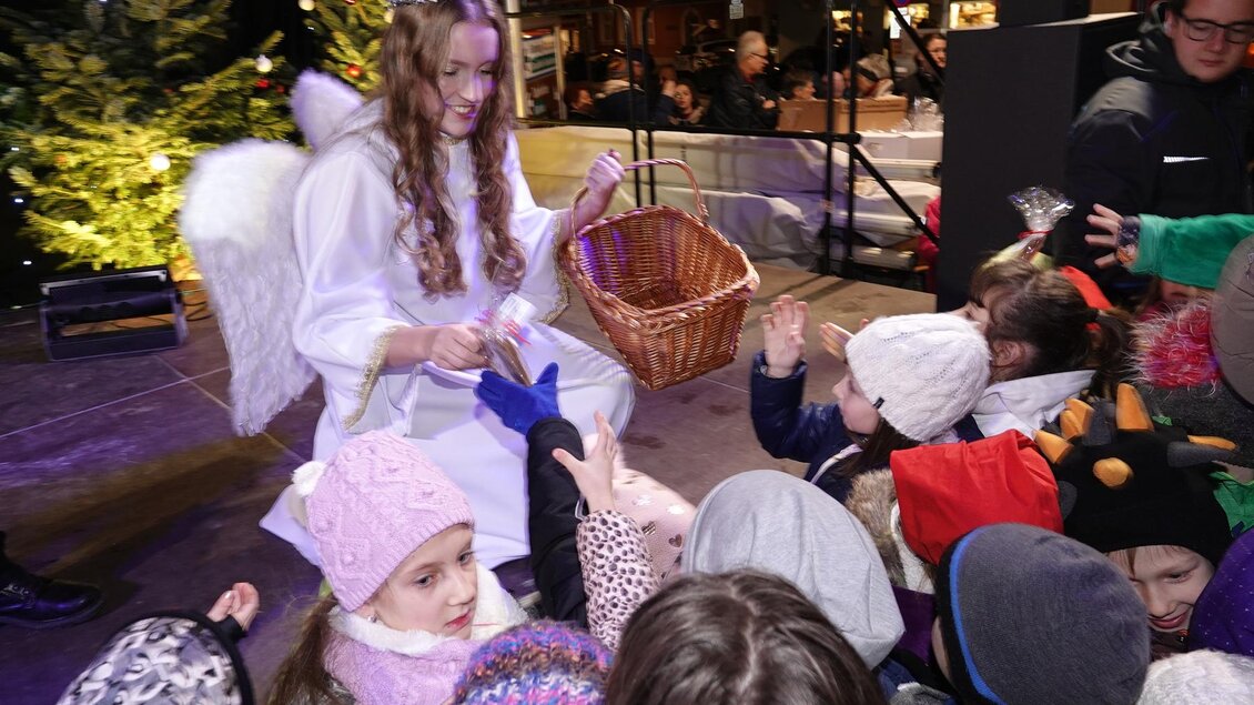 Ein Engel verteilt Süßigkeiten an eine Gruppe von Kindern. Die festliche Atmosphäre ist durch weihnachtliche Dekorationen geprägt. | © Tourismusverband Oststeiermark