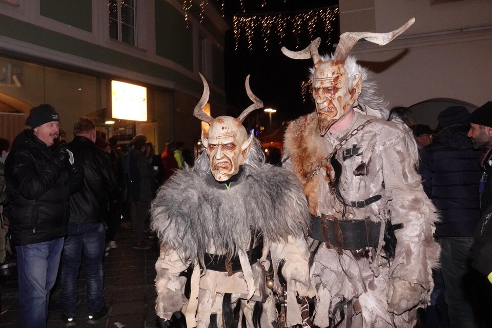 Zwei Menschen in fantasievollen Kostümen mit Hörnern und furchterregenden Masken stehen auf einer Straße. Im Hintergrund sind andere Zuschauer zu sehen, die das Geschehen beobachten. | © Tourismusverband Oststeiermark