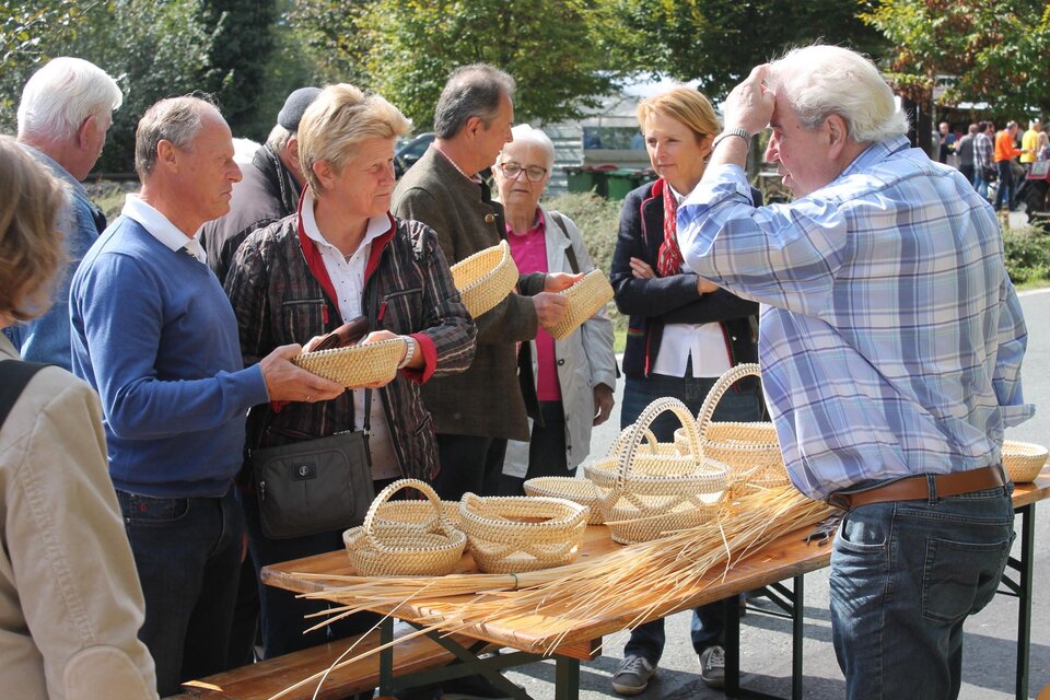 Eine Gruppe von Menschen betrachtet handgefertigte Körbe auf einem Markt. Die Atmosphäre ist lebhaft und die Besucher scheinen interessiert zu sein. | © Marktgemeinde Wies