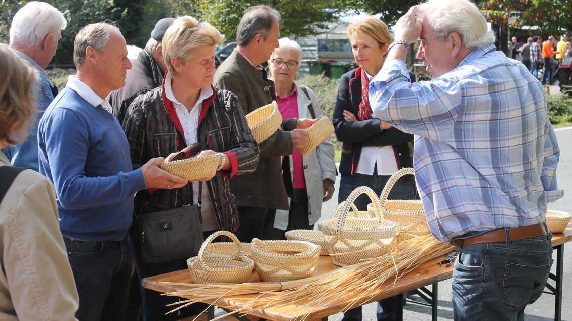 Eine Gruppe von Menschen betrachtet handgefertigte Körbe auf einem Markt. Die Atmosphäre ist lebhaft und die Besucher scheinen interessiert zu sein. | © Marktgemeinde Wies