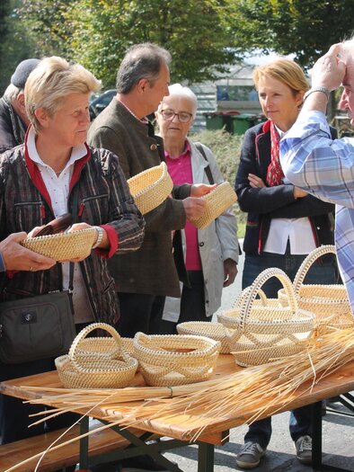 A group of people is looking at handmade baskets at a market. The atmosphere is lively and the visitors seem to be interested. | © Marktgemeinde Wies