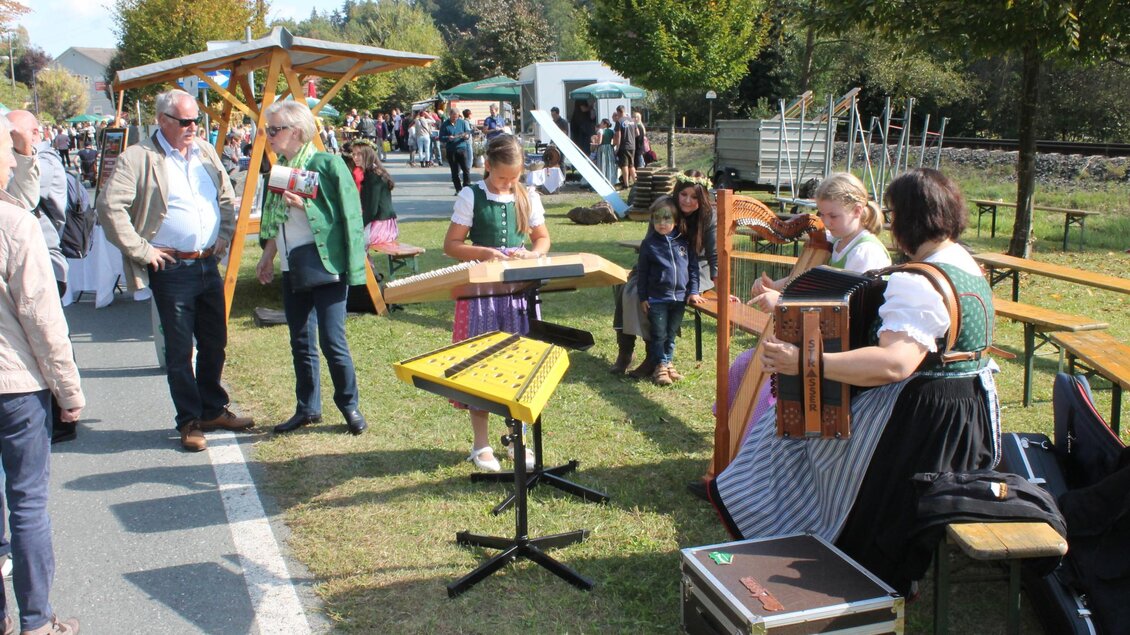 Ein lebhaftes Fest mit Musikern, die traditionelle Instrumente spielen. Im Hintergrund sind zahlreiche Besucher auf einer Straße zwischen grünen Bäumen. | © Marktgemeinde Wies