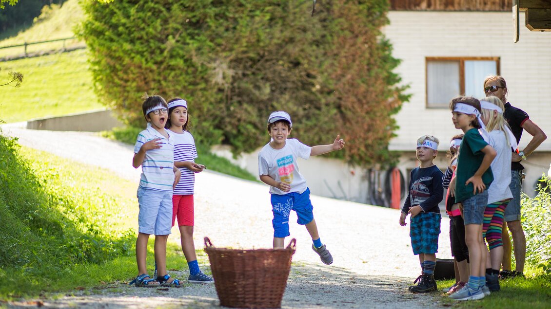 Eine Gruppe von Kindern spielt in der Natur. Sie tragen Kopfbedeckungen und scheinen aktiv an einem Spiel teilzunehmen. | © Dominik Steiner