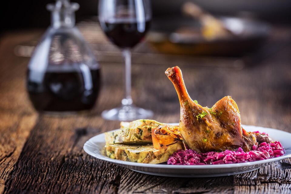 Ein köstliches Gericht mit gebratenem Hähnchenschenkel, Beilagen und roter Sauce. Im Hintergrund steht ein Glas Rotwein.