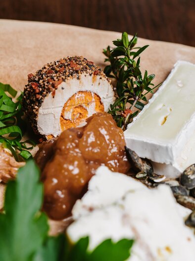 Ein Teller mit verschiedenen Delikatessen, darunter Käse, Nüsse und ein mit Gewürzen umhülltes Ei. Frische Kräuter und grüne Zwiebeln ergänzen das Bild. | © Michaela Lorber