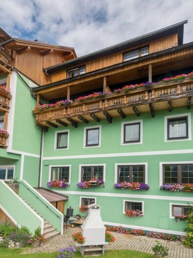 <p>The apartment restaurant Schwaiger, decorated with flowers on the balconies. The facade is painted green and there is a cozy atmosphere.</p> | © Hotel Schwaiger