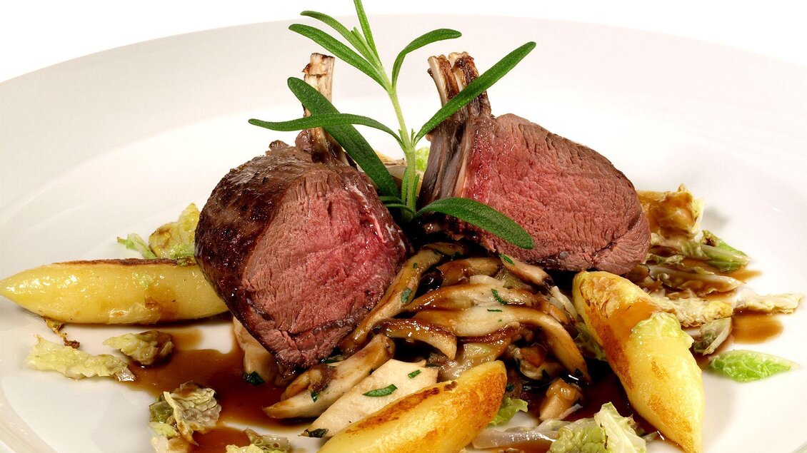 Ein elegantes Gericht mit zwei Lammkoteletts, attraktiv angerichtet. Dazu gibt es gegrilltes Gemüse und eine aromatische Sauce. | © Tourismusverband Oststeiermark