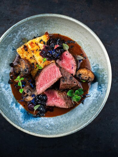 An attractively arranged plate with tender meat, side dishes, and a dark sauce. The colors and textures create an appetizing impression. | © Adobe Stock